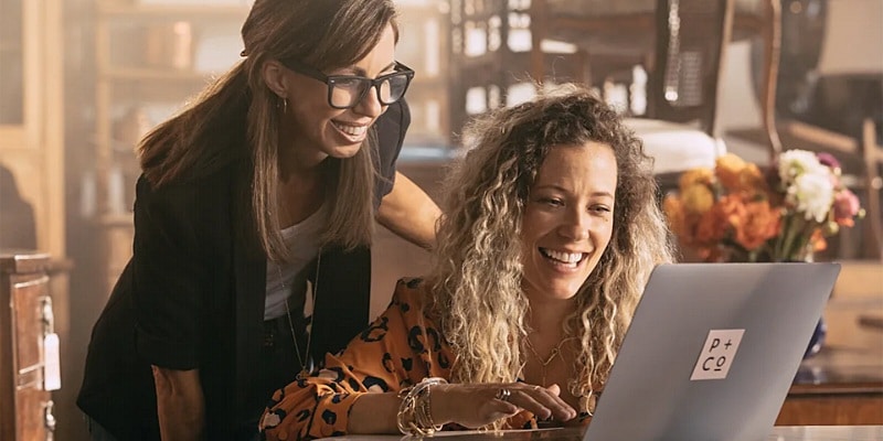 Due donne felici mentre osservano il monitor del notebook - Come guadagnare con Fiverr