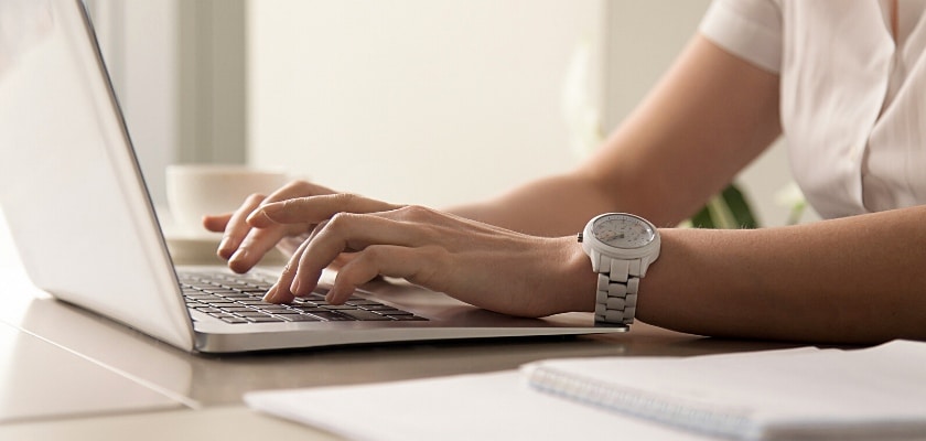 Mani di una donna che digitano sul computer portatile sul posto di lavoro – Guida alla Seo on page