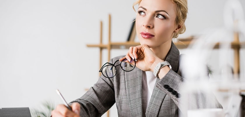 Ritratto di una donna d’affari pensierosa che distoglie lo sguardo mentre è seduta sul posto di lavoro – Quanto si può guadagnare con un blog