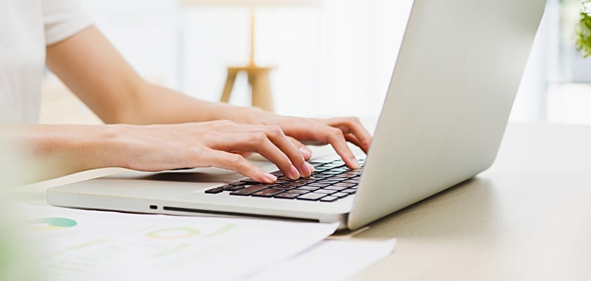Vista laterale dimezzata di una giovane imprenditrice asiatica che lavora con il computer portatile nel soggiorno di casa – Quanto si può guadagnare con un blog